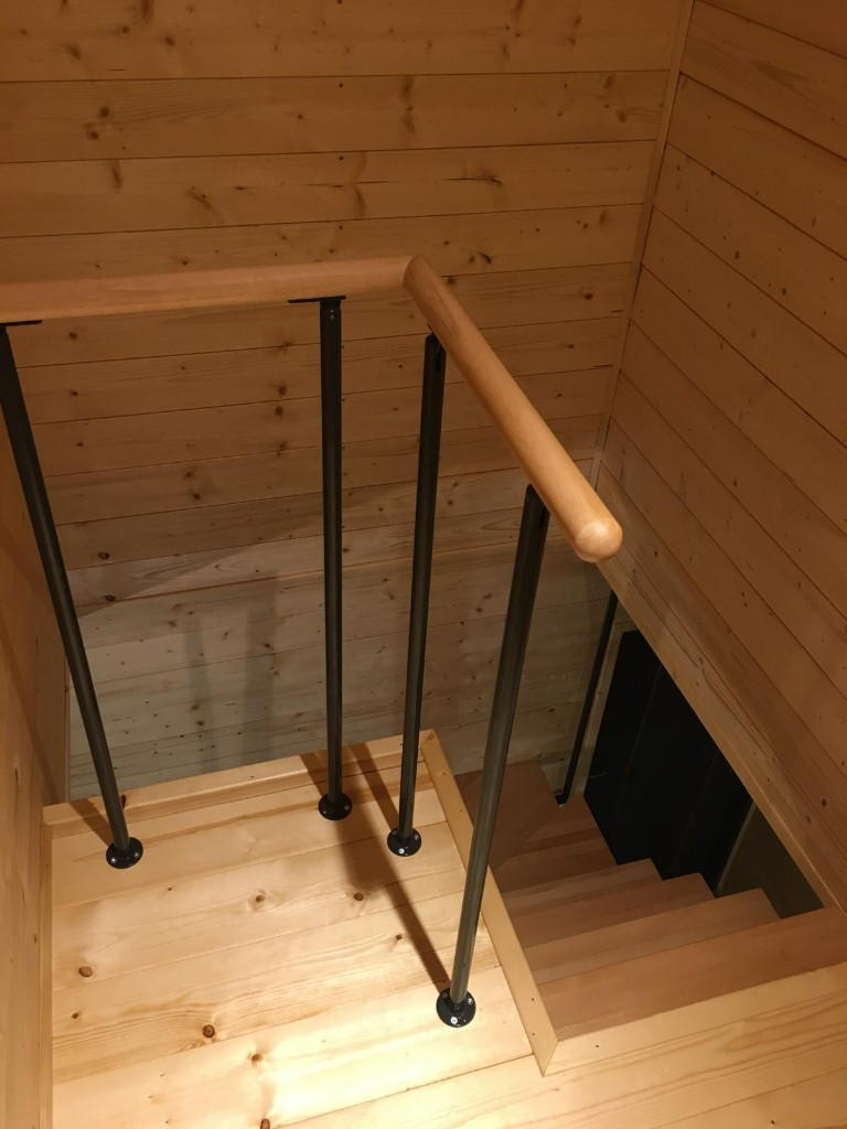 Drewniane schody wewnętrzne z poręczą i czarnymi balustradami
